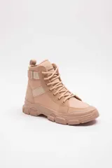 Bota militar beige con cordones, suela gruesa track y detalles de tiras elásticas en el lateral.
