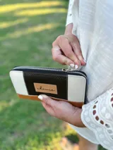 Billetera grande con cierre metálico, confeccionada en cuero. Presenta un diseño de bloques de color: negro texturado en el centro, beige texturado a los lados y cuero marrón liso en la parte inferior. Incluye un parche de cuero con la inscripción "chawie".