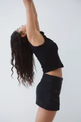 Musculosa corta negra de ajuste entallado en punto acanalado de algodón. Modelo con breteles y escote cuadrado con ribete de volado efecto arrugado que se prolonga por los hombros.