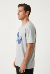 Remera blanca de manga corta, con cuello redondo y diseño gráfico estampado en el pecho con la palabra "waves" y formas geométricas en tonos azules.