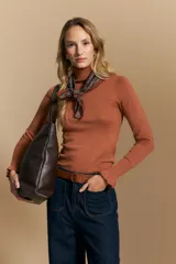 Polera de tejido fino color negro, con cuello alto y mangas largas con terminación sutilmente fruncida. Diseño ajustado al cuerpo.