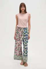 Pantalon de corte relajado y pierna ancha, confeccionado en rayón con estampado floral multicolor. Presenta cintura elástica con cordón ajustable decorado con borlas en los extremos.