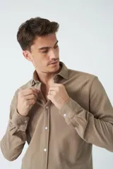 Camisa manga larga color beige, de corte regular, con cuello clásico y cierre frontal con botones.