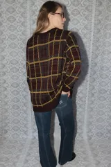 Buzo tejido de punto con diseño de cuadrillé en tonos bordó, verde y amarillo. Presenta cuello redondo, mangas largas y un detalle de cisne bordado en el pecho.