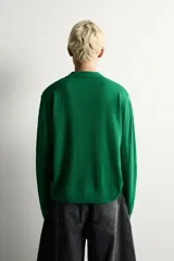 Polo de punto de manga larga en color verde, confeccionado en hilatura de lana. Presenta cuello solapa, cierre frontal con botonadura y acabados en rib en puños y bajo.
