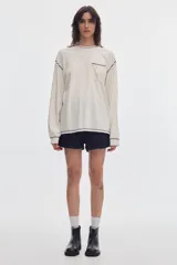 Remera de manga larga negra con bolsillo frontal en el pecho y costuras a la vista en contraste de color gris.