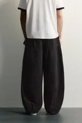 Pantalón barrel fit de mezclilla color verde militar, con efecto lavado, cinco bolsillos, cierre frontal con cremallera y botón, y detalle de pinzas en las rodillas.