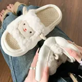 Pantuflas abiertas de diseño lúdico con forma de oveja, confeccionadas en piel sintética blanca con detalles bordados en el rostro y orejas laterales. Poseen una suela de goma gruesa y resistente.
