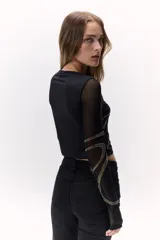 Remera negra de mangas largas transparentes, con apliques de brillos formando ondulaciones.