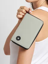 Billetera gris rectangular con cierre de cremallera y logo circular negro en la esquina inferior.