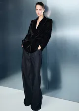 Blazer de terciopelo negro con cuello de solapa, cierre frontal cruzado con botones y mangas largas con puños abotonados. Presenta un diseño recto con bolsillos de solapa en la parte frontal y forro interior.