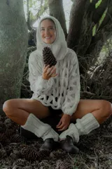 Buzo de tejido de punto calado con diseño de red, cuello redondo y mangas largas abullonadas. Presenta una textura jaspeada en tonos gris y blanco.