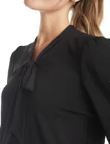 Blusa de seda fría color negro, con escote en V y lazo decorativo al cuello. Presenta mangas largas abullonadas con puños elásticos y detalles de strass aplicados en cuello, lazo y mangas.