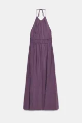 Vestido midi de color morado con cuello halter, tirantes finos ajustables y espalda descubierta. Cuenta con detalles fruncidos en el delantero y la cintura.