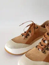 Zapatillas deportivas de cuero color camel con cordones marrones y suela blanca.