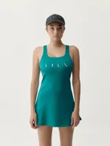 Vestido deportivo turquesa con sujetador integrado y copas extraíbles, confeccionado en tejido Shapplex_B, compacto y ligero. Cuenta con puntos reflectantes en la espalda y diseño de corte evasé con short interno.