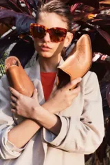 Mule de cuero color suela con diseño de punta fina y bordado decorativo en el empeine. Presenta un taco bajo de madera y una silueta abierta en el talón.
