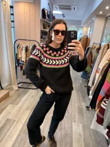 Sweater de punto tejido en mohair, color negro con diseño de guardas geométricas en tonos fucsia, verde neón y blanco en la zona del canesú. Presenta cuello redondo y mangas largas.