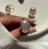 Anillo dorado con una perla irregular blanca.