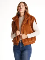 Chaleco de piel sintética en color beige, con cuello alto, cierre frontal metálico y terminaciones en tejido rib en el ruedo y sisas.