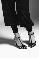 Pantalón negro de tiro bajo, confeccionado en terciopelo con pequeños puntos brillantes. Presenta cintura elástica con pliegues, caída ancha tipo baggy y puños ajustados en los tobillos.