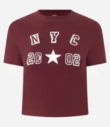 Remera corta color bordó de algodón con elastano, cuello redondo y mangas cortas. Estampa frontal con letras "NYC" y el número "2002" con una estrella en el medio.