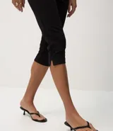 Pantalón capri negro de malla crepé, con pliegues delanteros y sin estampado.