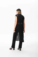 Chaleco largo sin mangas de tejido de punto negro, con trama artesanal calada y caída suave.