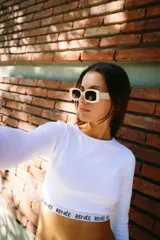 Crop top blanco de algodón con lycra, cuello redondo, manga larga y cintura con elástico afelpado con la inscripción 'RENÉE'.