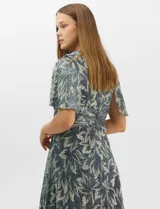 Vestido largo de fiesta con diseño cruzado, escote en V y drapeado lateral en la cintura. Presenta mangas cortas acampanadas y falda amplia con caída fluida. Confeccionado en tejido liviano con acabado plisado y estampado floral metalizado.