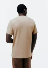 Remera de manga corta color beige, con cuello redondo y cartera con tres botones frontales.