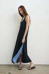 Vestido largo de tejido acanalado color negro, con escote redondo, tirantes anchos y aberturas laterales que revelan un tono celeste en el interior.