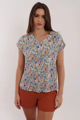 Blusa estampada con flores de colores sobre fondo blanco, con cuello en V y mangas cortas.