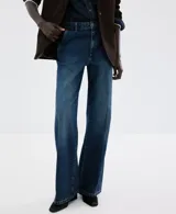 Jeans de tiro medio y corte wide leg, confeccionados en denim de algodón azul oscuro con lavado uniforme. Presentan cierre frontal con botón y cremallera, bolsillos laterales y traseros, y trabillas para cinturón.