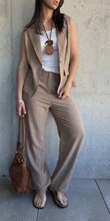 Pantalón de vestir color tostado con finas rayas verticales blancas, de corte palazzo y tiro alto.