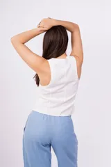 Chaleco corto sin mangas color verde salvia, confeccionado en tela perforada (broderie o calado). Presenta escote en V con lazos ajustables en el centro frontal.