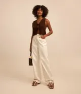 Pantalón wide leg color crudo confeccionado en sarga con pespuntes contrastantes, cintura alta con trabillas, cierre por botón y cremallera, bolsillos delanteros y traseros.