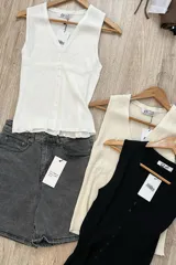 Musculosa blanca de punto acanalado, con escote en V y botones frontales.