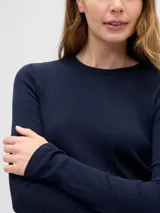 Remera de manga larga confeccionada en tejido rib, con cuello redondo y ajuste al cuerpo.