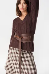 Faja ancha de cuero marrón chocolate con costuras decorativas contrastantes, cierre de nudo envolvente y trabilla lateral. Lleva la marca Petra grabada.
