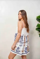 Vestido corto color beige de corte holgado, con tirantes finos y diseño sin mangas. Presenta bordados florales en tonos azules y marrones en todo el frente y un detalle bordado en el borde inferior.