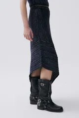 Falda larga de punto acanalado con diseño de rayas en tonos oscuros y acabado brillante por la incorporación de fibra metálica. Presenta un ruedo asimétrico y un calce entallado que se ensancha hacia la base.