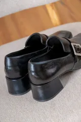 Mocasín de cuero vacuno color azul, con punta cuadrada, taco bloque bajo y detalle de tira con hebilla metálica plateada en el empeine.
