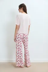 Pijama compuesto por una remera de manga corta en color rosa claro con un pequeño bordado de labios en el pecho y un pantalón largo estampado con motivos de labios en tonos rojos y rosas.