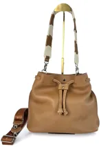 Bolso tipo bucket de cuero color marrón con cierre de cordón ajustable. Incluye dos correas intercambiables: una corta de cuero para llevar al hombro y una larga de tela con letras para usar como bandolera. Sin forro interior.