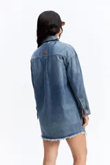 Vestido tipo camisa de jean con calce holgado, cuello clásico, cierre frontal con botones y ruedo con terminación desflecada.