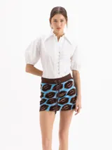 Camisa de poplín de algodón color blanco, con cuello camisero clásico, mangas abullonadas al codo con puño elástico y cierre frontal con botones.