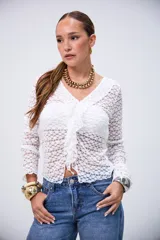 Blusa blanca de encaje con cuello en V, volados en el frente y mangas largas.