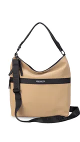 Cartera tipo hobo de tamaño grande en color beige, con detalles en negro. Presenta una franja horizontal negra con el logo de la marca, asa corta de hombro y correa larga desmontable. Incluye bolsillo frontal con cierre oculto y bolsillo trasero.