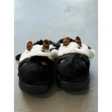 Pantuflas de peluche con diseño de vaca, confeccionadas en piel sintética suave. Cuentan con suela de goma antideslizante y diseño abierto en el talón.